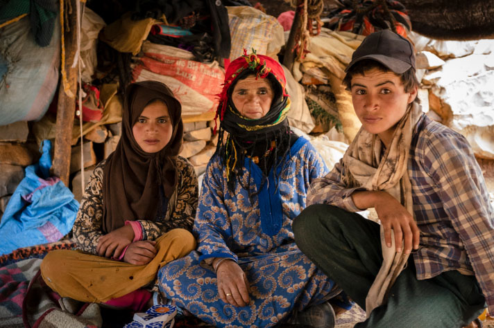 A woman and two children in front of sacks