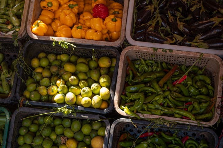 Peppers, cucumbers, limes and aubergines in large crates